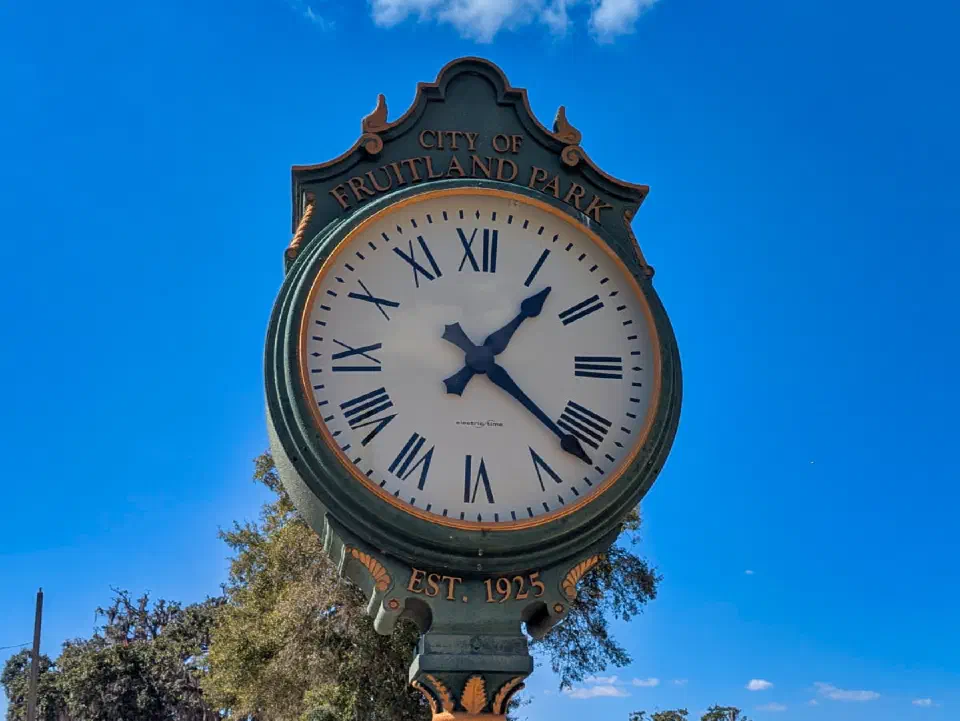 Clock in front of Fruitland Park City Hall, established 1925, under a clear blue sky.