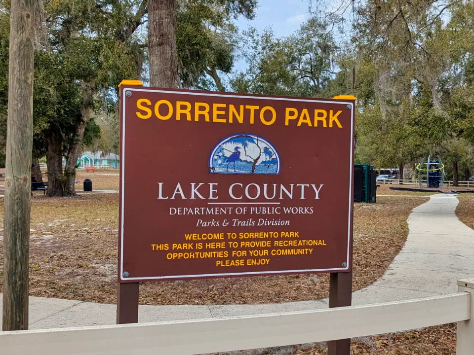 Sign for Sorrento Park in Sorrento, Florida, with trees and sky visible in the background.
