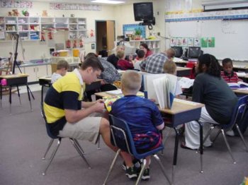 Group of alee students reading to students at an elementary school.